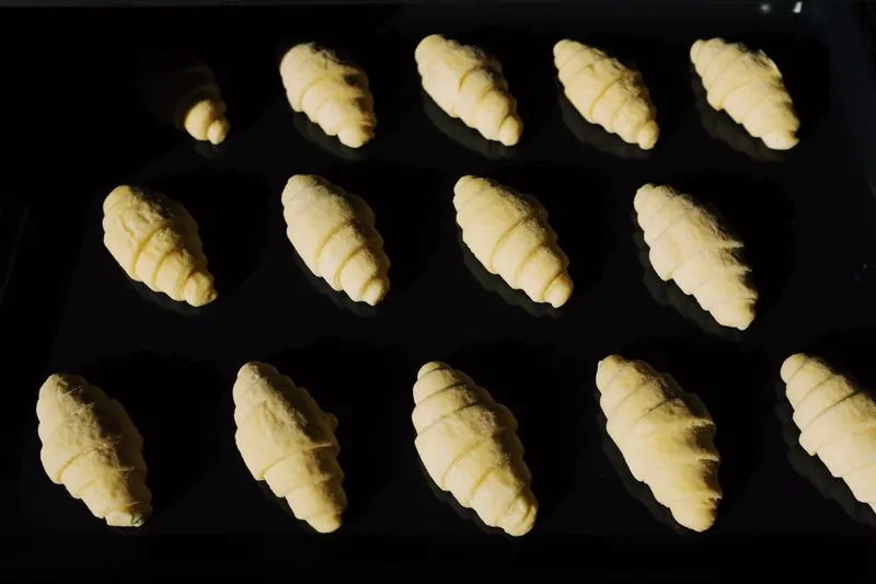 Raw croissants laid out on a black tray