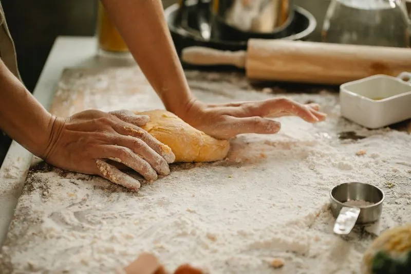 A baker kneading dough on a floured surface